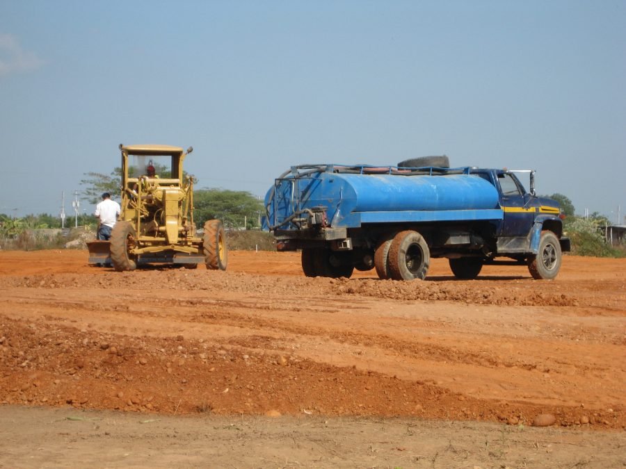 Motoniveladora y camión cisterna en movimiento de tierra